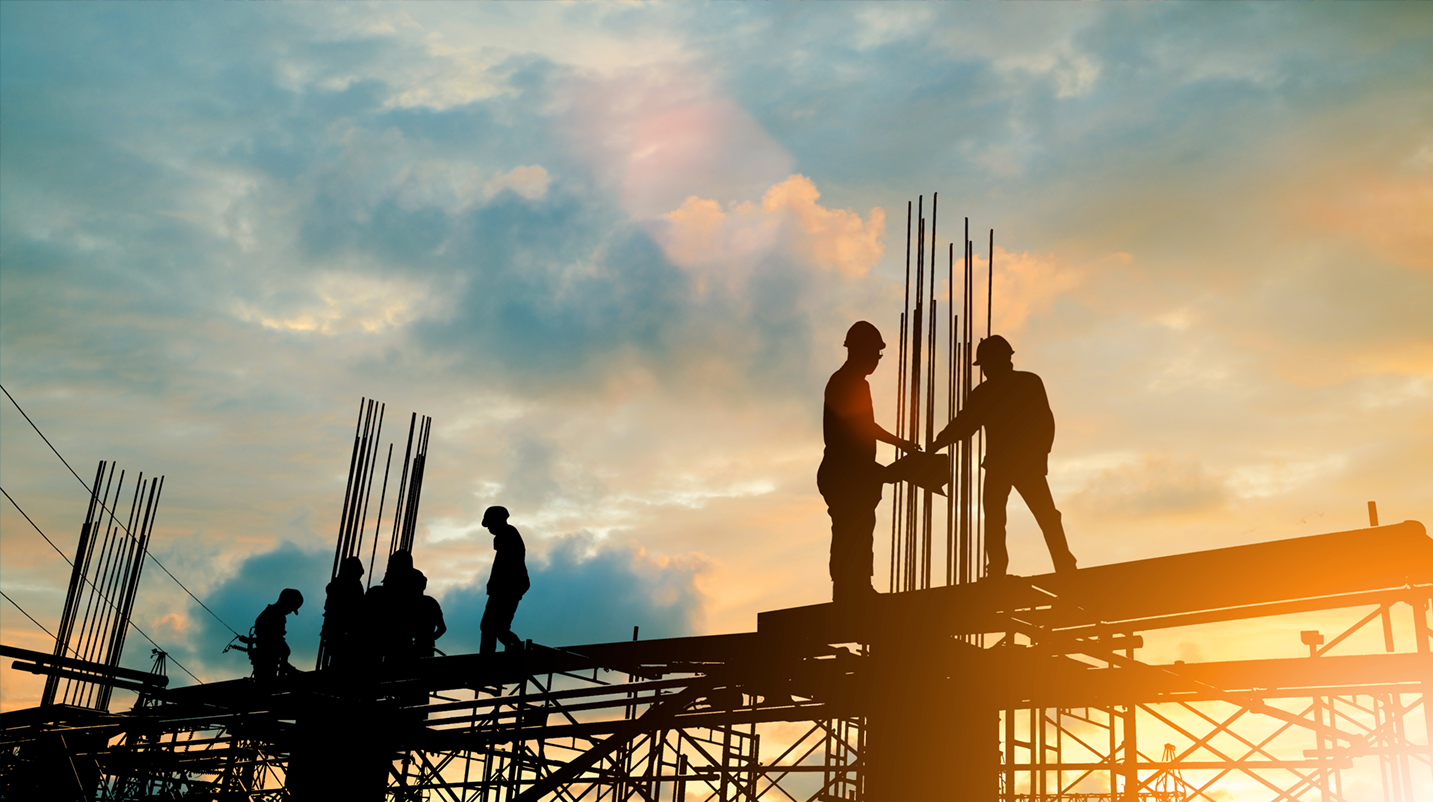 Construction workers building with metal at sunset